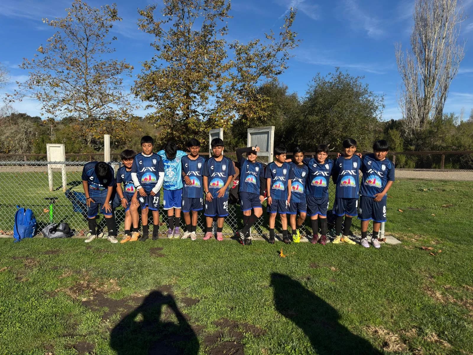 Young soccer players in Chilangolandia-branded blue uniforms lined up outdoors on a sunny game day.